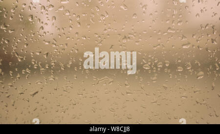 Rain Drops On Surface of wet Window Glass pane In Rainy Season. Abstract background. Natural Pattern of raindrops isolated from outdoor cloudy environ Stock Photo