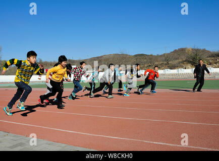 --FILE--Students run on the playground during a sports lesson at a primary school in Yantai city, east Chinas Shandong province, 26 November 2014. Stock Photo