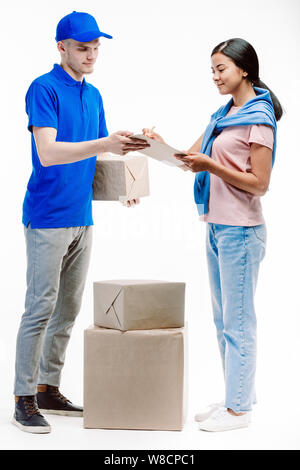 Postman in blue uniform checks the adress on the parcel with the help of the woman client wearing pink shirt. Stock Photo