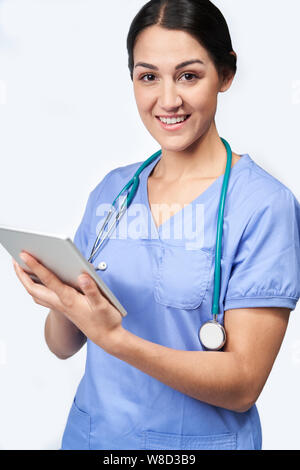 Studio Portrait Shot Of Female Nurse Wearing Scrubs Using Digital Tablet Stock Photo