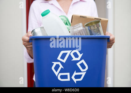 Close Up Of Woman Holding Recycling Bin Of Reusable Waste Outside Front Door Stock Photo