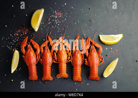 lobsters with lemon lime and dry pepper on black background top view Stock Photo