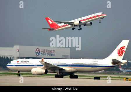 --FILE--An Airbus A330-300 passenger jet of Air China, front, taxis as a Boeing plane of Shanghai Airlines takes off at the Hongqiao International Air Stock Photo