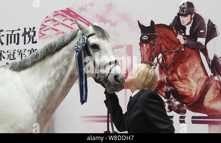 British etiquette expert Diana Mather kisses a horse at an equestrian exhibition at CITIC Pacific Plaza ahead of the 2015 Shanghai Longines Global Cha Stock Photo