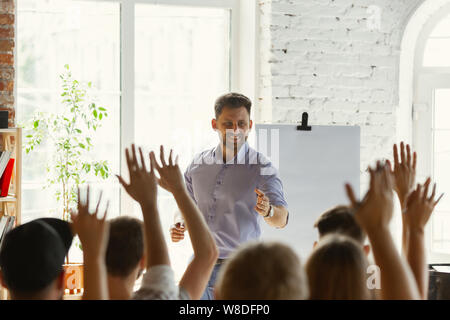 Male speaker giving presentation in hall at university workshop. Audience or conference hall. Rear view of unrecognized participants in audience. Scientific conference event, training. Education concept. Stock Photo