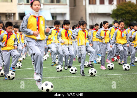 Young Chinese students perform a football exercise at Duqiao Primary School in Linhai city, east China's Zhejiang province, 26 March 2015.   China is Stock Photo