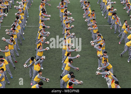 Young Chinese students perform a football exercise at Duqiao Primary School in Linhai city, east China's Zhejiang province, 26 March 2015.   China is Stock Photo
