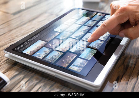 Young Male Editor Searching Photos On Tablet In Office Stock Photo