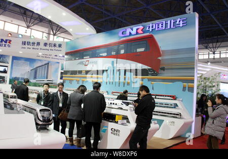 --FILE--Chinese visitors look at models of CRH (China Railway High-speed) bullet trains and subway trains on display at the stand of China CNR Corpora Stock Photo