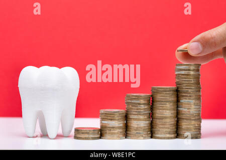 Man Placing Coin On Top Of The Stack Coins In Front Of White Tooth Stock Photo
