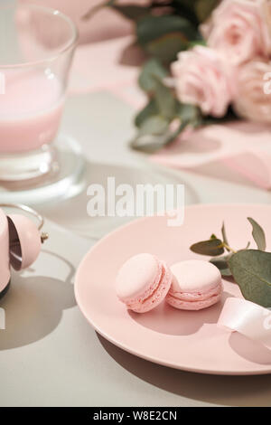 macaroons in pastel colors with bouquet of pink roses flowers on white background. Beautiful holiday background. copy space. Stock Photo