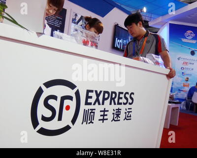 --FILE--Chinese employees talk at the stand of SF Express during an exhibition in Beijing, China, 29 May 2013.   SF Express, a leading Chinese express Stock Photo