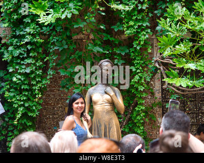 Tourist poses for a photo next to Juliet's statue at Juliet's house in Verona, Italy. Stock Photo