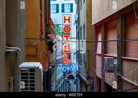 Genoa (Genova), Italy - June 30, 2019: Red neon hotel sign on the wall in the narrow street in Genoa Stock Photo