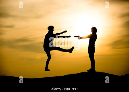 Silhouette  woman pointing at the man on the sunset background