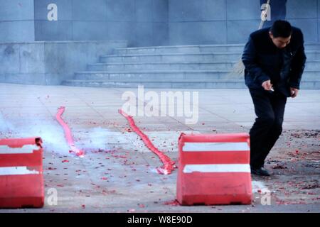 A man runs away after igniting firecrackers on a street to celebrate the Chinese Lunar New Year in Qingdao city, east China's Shandong province, 25 Fe Stock Photo