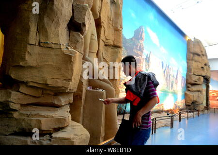 A believer places banknotes near Buddha statues to pray for good luck at the Gansu Museum in Lanzhou city, northwest China's Gansu province, 19 May 20 Stock Photo