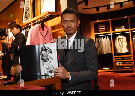 Chinese badminton star Lin Dan poses with his photo album at a signing event in Beijing, China, 20 March 2015. Stock Photo