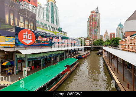 Bangkok - Thailand, 3 Aug 2019: Pratunam pier, express boat public transport stop in center of city. Saen Saep canal. Busy traffic on Ratchadamri road Stock Photo