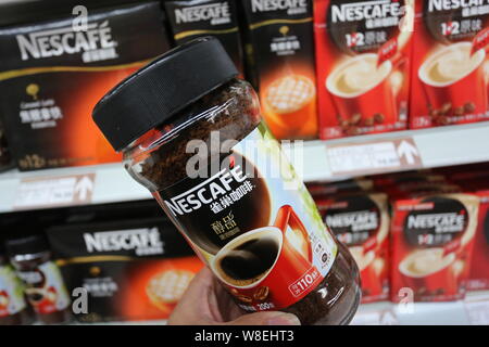 --FILE--A customer buys a bottle of Nescafe instant coffee of Nestle at a supermarket in Xuchang city, central Chinas Henan province, 7 December 2014. Stock Photo