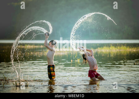 asian children playing splashing water in the river. Stock Photo