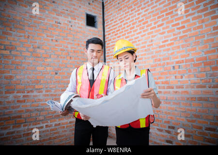 woman and man working with old brick wall background at construction site,engineering concept Stock Photo