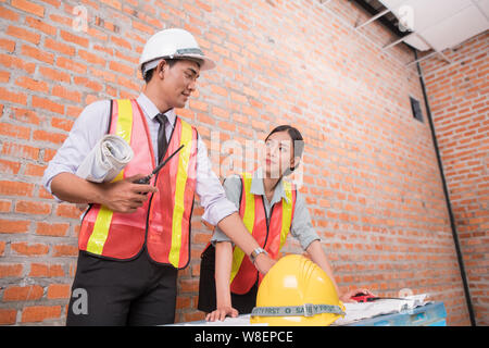 woman and man working with old brick wall background at construction site,engineering concept Stock Photo