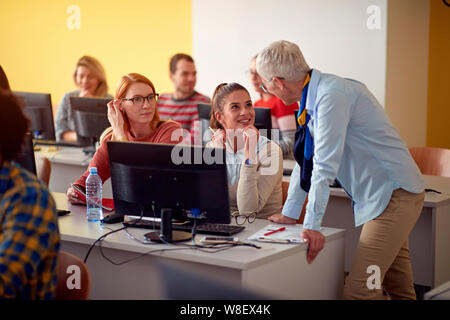 lecturer helping smiling students on project Stock Photo