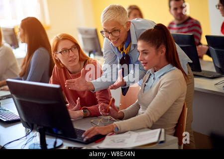 teacher helping smiling students on project on university campus Stock Photo
