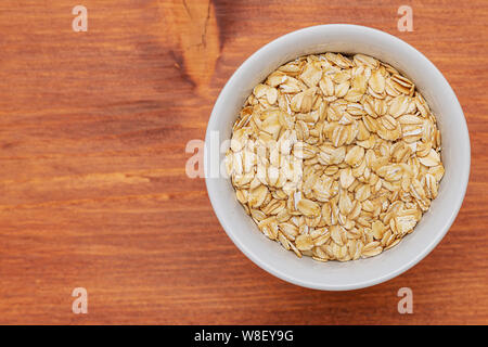 Uncooked bulgur in a white bowl on brown wooden background. Top view, copy space, minimal idea Stock Photo