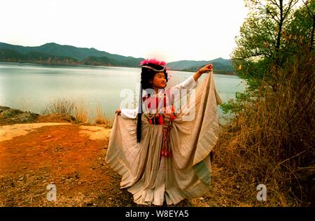 A Mosuo minority young girl dressed in traditional clothes dances at the Lugu Lake which is situated in the mountains bordering southwest Chinas Sichu Stock Photo