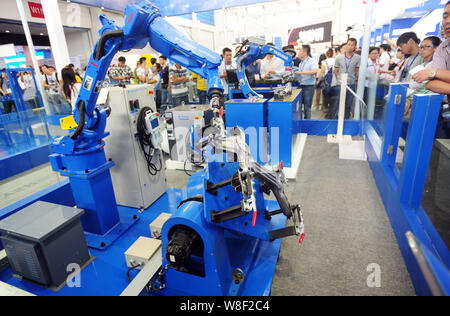 --FILE--Visitors look at robot arms of Yaskawa on display during the 14th China International Equipment Manufacturing Exposition in Shenyang city, nor Stock Photo