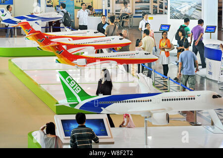 --FILE--Visitors look at models of C919 and ARJ21 jet planes at the stand of COMAC (Commercial Aircraft Corporation of China, Ltd.) during the Fifth S Stock Photo