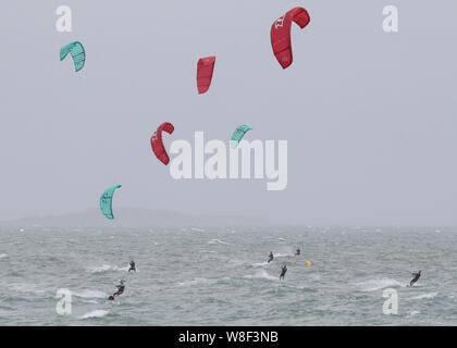 Kite surfers enjoy the strong winds off of Branksome Chine, near Poole in Dorset. Warnings for rain and wind came into force across nearly all of the UK today. Stock Photo