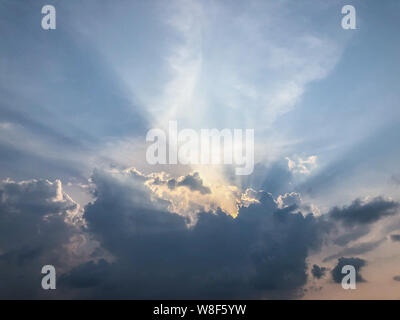 Rays of sunlight through dark clouds at sunset Stock Photo