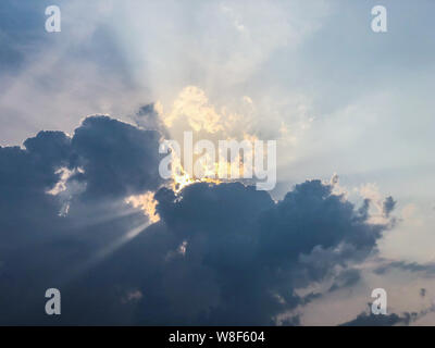 Rays of sunlight through dark clouds at sunset Stock Photo