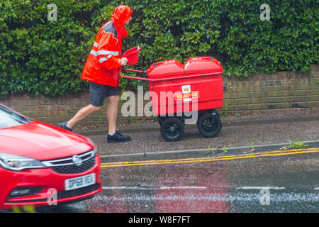 Bournemouth, Dorset UK. 9th Aug 2019. UK weather: the bad weather has arrived as torrential rain falls in Bournemouth. Postman wearing shorts hurries on his rounds regardless of the weather, trying to avoid getting splashed by cars going through puddles as they pass!   Credit: Carolyn Jenkins/Alamy Live News Stock Photo
