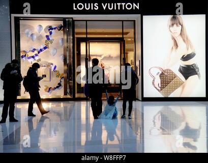 FILE--Shoppers walk past the fashion boutique of Louis Vuitton (LV