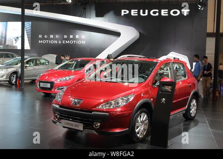 FILE--A Dongfeng Peugeot Cross 307, front, is displayed as employees clean  a Dongfeng Peugeot 308 during an automobile exhibition in Shanghai, China  Stock Photo - Alamy