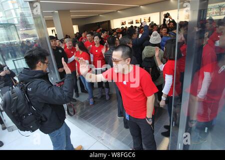 Chinese employees welcome customers at the newly-opened Apple store in Shenyang city, northeast Chinas Liaoning province, 28 February 2015.      The f Stock Photo