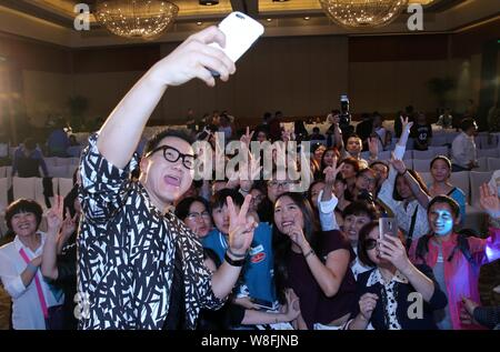 South Korean singer Jeong Soon-won, left, better known by his stage name The One, takes selfies with fans during a press conference for his Chinese al Stock Photo