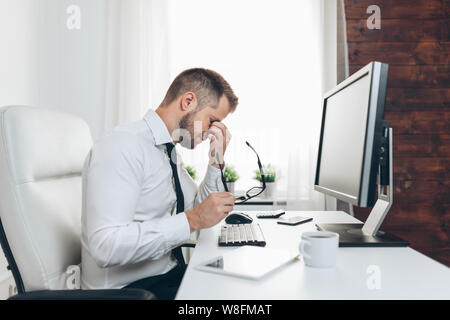 Tired businessman from heavy workload sitting at the desk Stock Photo