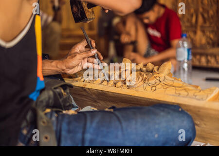 Master wood-carver made using a special knife wooden national dish - a ladle with a patterned handle. A fragment of a close-up of his hands Stock Photo