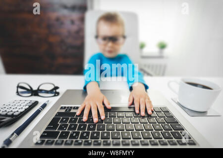 Cute child with glasses learning how to use a laptop Stock Photo