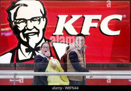 --FILE--Pedestrians walk past a fastfood restaurant of KFC in Huaian city, east China's Jiangsu province, 14 February 2015.   KFC, the world's largest Stock Photo