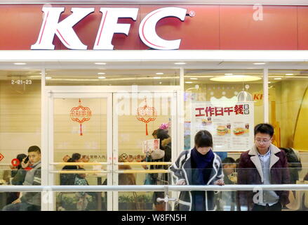 --FILE--Pedestrians walk past a fastfood restaurant of KFC in Huaian city, east China's Jiangsu province, 14 February 2015.   KFC, the world's largest Stock Photo