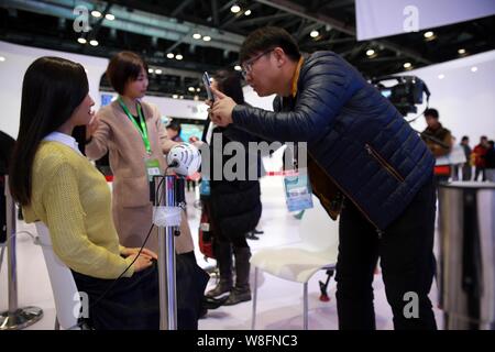 A visitor takes photos of humanoid robot Geminoid F, produced by renowned robot designer Hiroshi Ishiguro of Osaka University, is on display during th Stock Photo