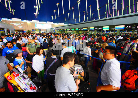 --FILE--A crowd of passengers queue up in front of counters of airlines after their flights were delayed or cancelled due to thunder storms at the Sha Stock Photo