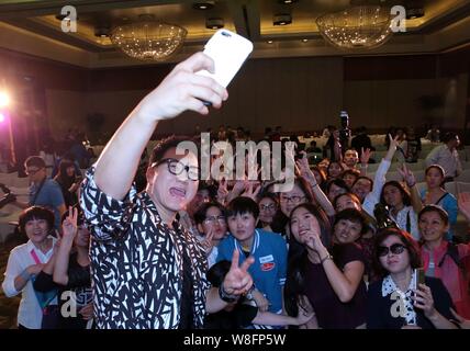 South Korean singer Jeong Soon-won, left, better known by his stage name The One, takes selfies with fans during a press conference for his Chinese al Stock Photo