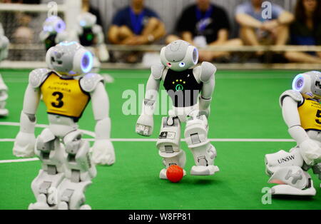 Robots of Australian team UNSW (University of New South Wales), yellow, and German team B-Human compete during the final game of the 19th RoboCup in H Stock Photo